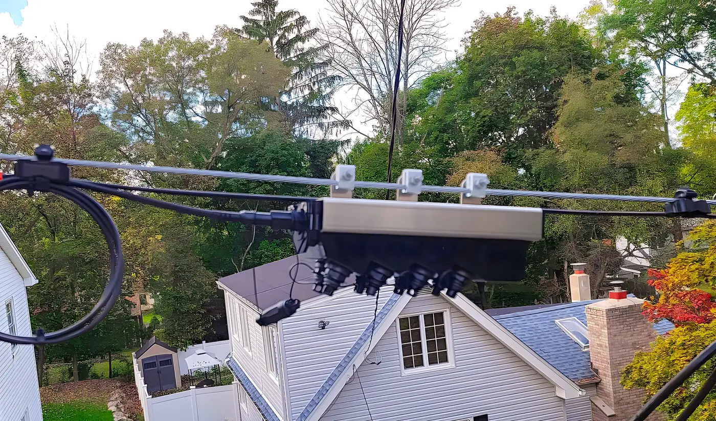 Aerial FTTH distribution point with a terminal enclosure on strand and drop cables running to houses